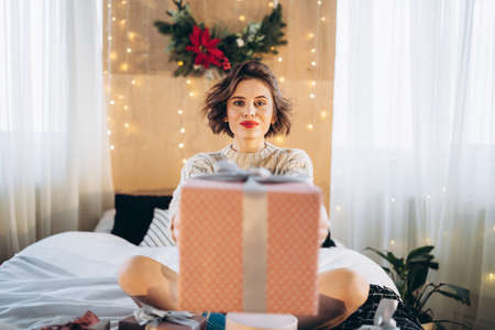 Happy and pretty brunette on the bed with gift boxes around her. New Year, Christmas, birthday, Valentineâs Day conceptの写真素材