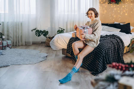 Happy and pretty brunette on the bed with gift boxes around her. New Year, Christmas, birthday, Valentineâs Day conceptの写真素材