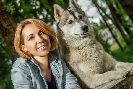 A girl in nature with a husky dog in sunny weatherの写真素材