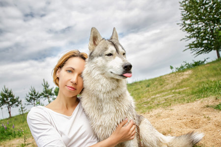 A girl in nature with a husky dog in sunny weather