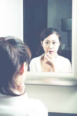 Women who have a makeup to look in the mirrorの写真素材