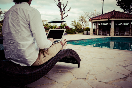 Man to operate the personal computer by the poolの写真素材