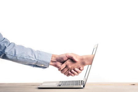 Handshake, hand coming out of laptop screenの写真素材