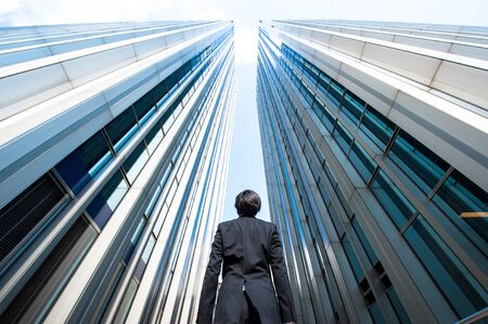 Businessman looking up at the high building, low angleの写真素材