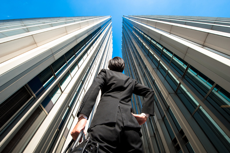 Businessman looking up at the high building, low angleの写真素材
