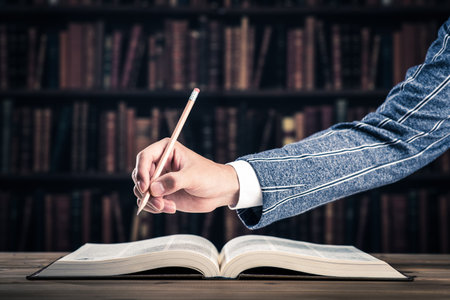 Thick book, hand holding a penの写真素材