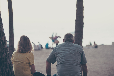 A couple of elderly people sitting on the beachの写真素材