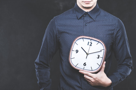 Men have a clock, dark background, studio shootingの写真素材