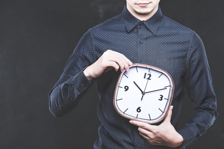 Men have a clock, dark background, studio shootingの写真素材
