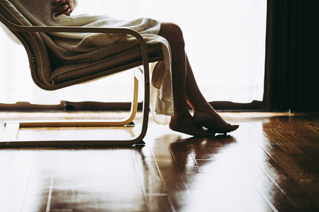 lonely woman sitting in a chair at the windowの写真素材