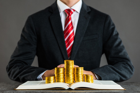 businessman and gold coin placed on a bookの写真素材