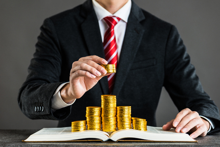 businessman and gold coin placed on a bookの写真素材