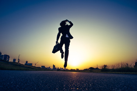 jumping businessman silhouette and morning sunの写真素材