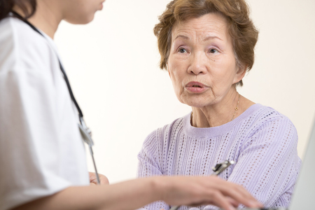 Asian elderly women talking to a doctorの写真素材