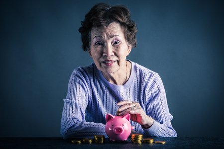 piggy bank and an Asian senior womanの写真素材