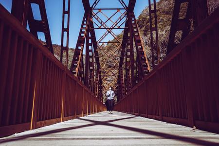 Asian lady running on the iron bridgeの写真素材