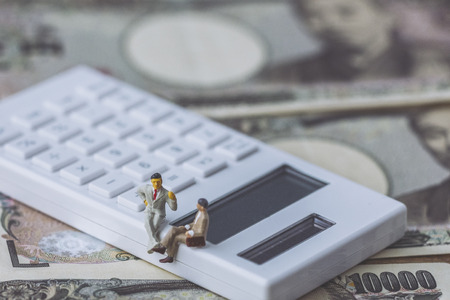 Miniature businessman and calculatorの写真素材