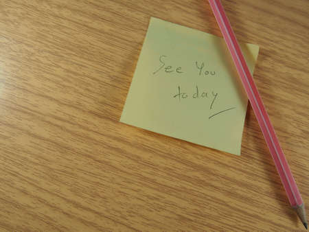 Reminder, see you today on yellow sticky note phrase with pink pencil on wood backgroundの写真素材