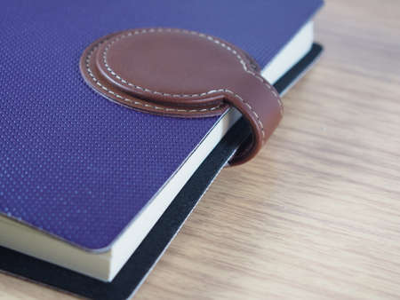 Purple business notebook with brown skin for closing on wood backgroundの写真素材