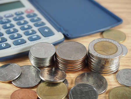 Pile of coins, baht money and calculator on wood backgroundの写真素材