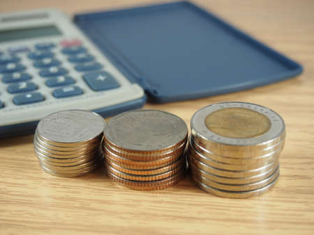 Count, pile of coins, money and calculator on wood backgroundの写真素材