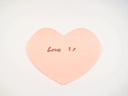 Love you writing on sticker note with pink heart shape, on the wallの写真素材