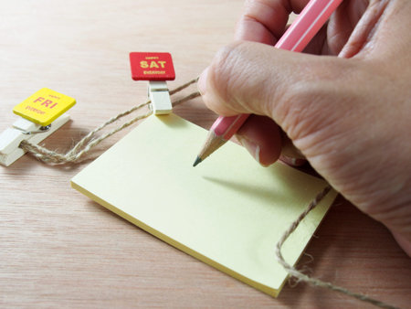 Taking note on yellow paper with attached red wooden paper clip, Saturday tagの写真素材