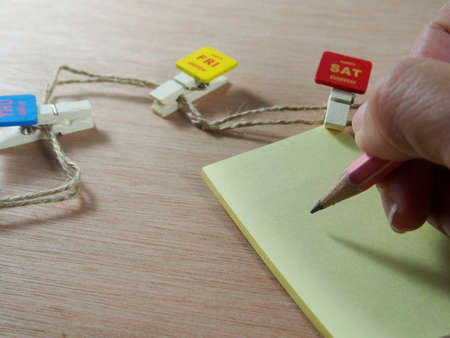 Writing on note paper with wooden paper clips as nice day, Saturdayの写真素材