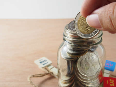 Holding coin, baht money on piggy bank glassの写真素材