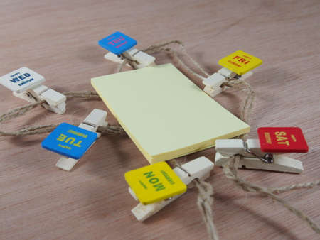 Yellow sticky paper with wooden paper clips as business daysの写真素材