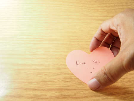 Taking pink sticky paper notes by hand, telling love youの写真素材