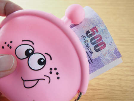 Rolled banknotes in pink purse with happy smiling, easy drawing on handbagの写真素材