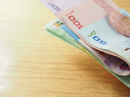 Expense, income, pile of Thai baht money in hand