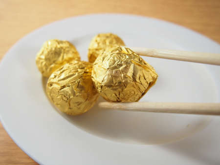 Taking by chopsticks, milk chocolate balls, covered aluminium foilの写真素材