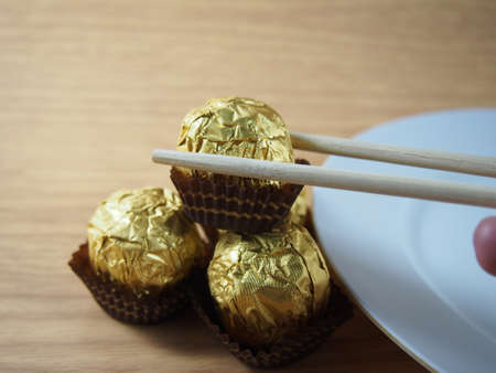 Taking by chopsticks,  milk chocolate balls, covered aluminium foil, souvenir in Valentines Dayの写真素材