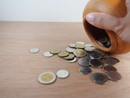 Thai baht coin, saving money in baked clay jar on wooden backgroundの写真素材