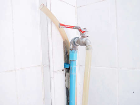 Old faucet water, broken joint on tile floorの写真素材