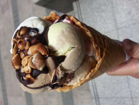 Peanuts topping with chocolate sauce on ice cream , crispy coneの写真素材