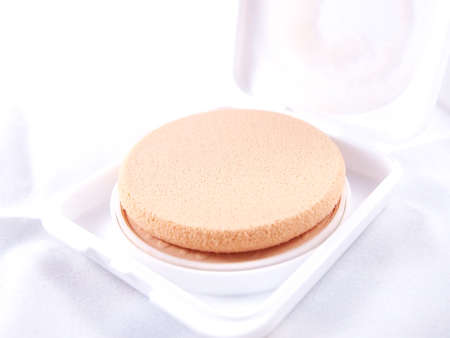 Puff, make-up sponge on beige powder refill on white backgroundの写真素材