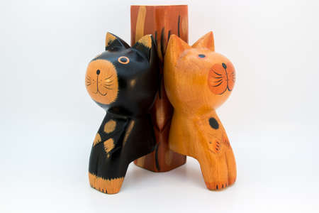 A black and a brown wooden cat sitting leaning on a stemの写真素材