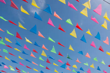 Lines of red,green,yellow,blue and pink flags in front of blue skyの写真素材