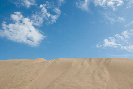 Blue sky with white clouds in the desert with one duneの写真素材