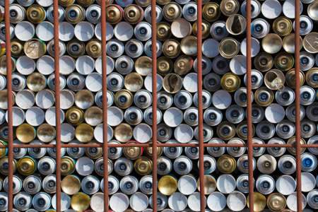 Dozens of stapled spray cans behind rusty barsの写真素材