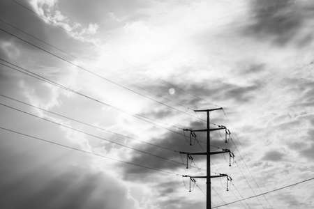 Power pole in threatening weather conditions, black clouds and the sunの写真素材
