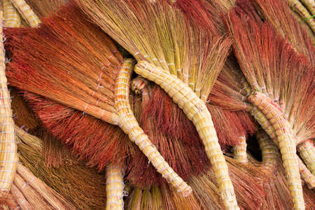 Pile of red and yellow handmade broomsの写真素材