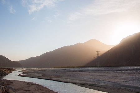 Sunrise between mountains over a river valley in Xinjiang Chinaの写真素材