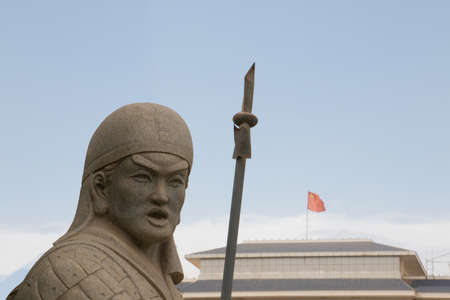 Fierce chinese stone soldier with a weapon next to china flagのeditorial素材