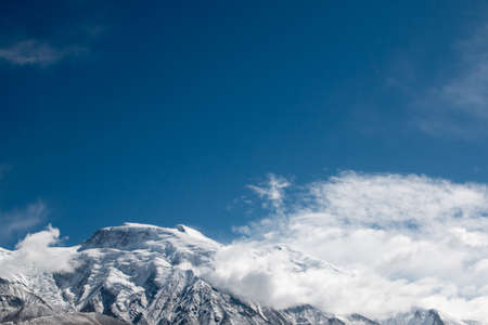 Top of a snow mountain with a cloudy blue sky in xinjiang chinaの写真素材