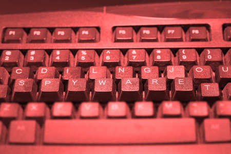 Keyboard with the keys spyware elevated in red lightの写真素材