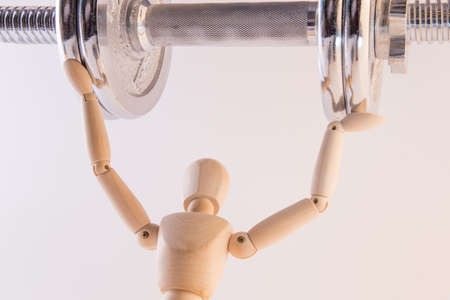 Puppet carrying heavy metal weight on a white backgroundの写真素材
